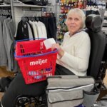 an elderly woman on a motorized wheelchair holding a shopping basket at a Meijer grocery store