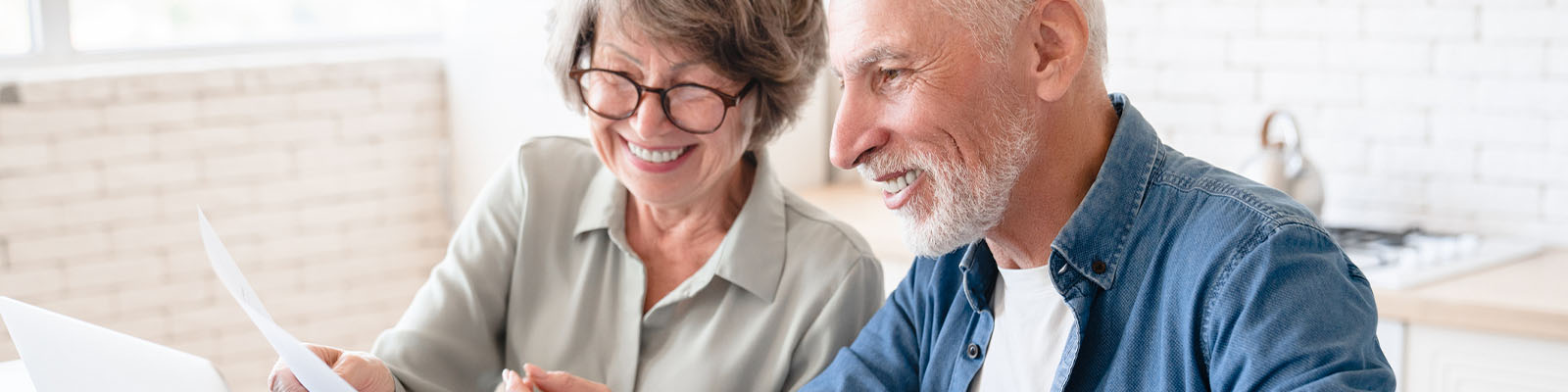 A senior man and woman looking at paperwork together and smiling