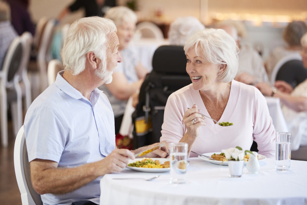 Male and female senior living residents enjoying a meal in the Grove City Senior living community dining room at a table