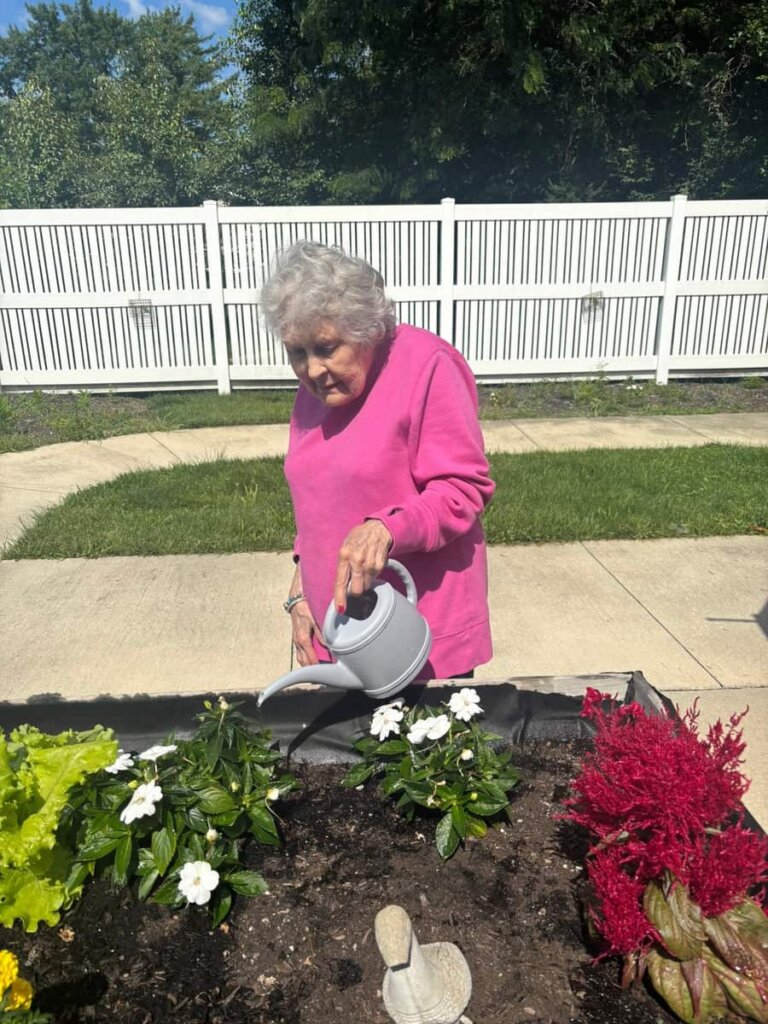 Resident watering flowers in the community garden at Grove City Senior Living